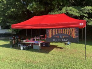 Competition BBQ set-up including tent, smokers, tables and other equipment.